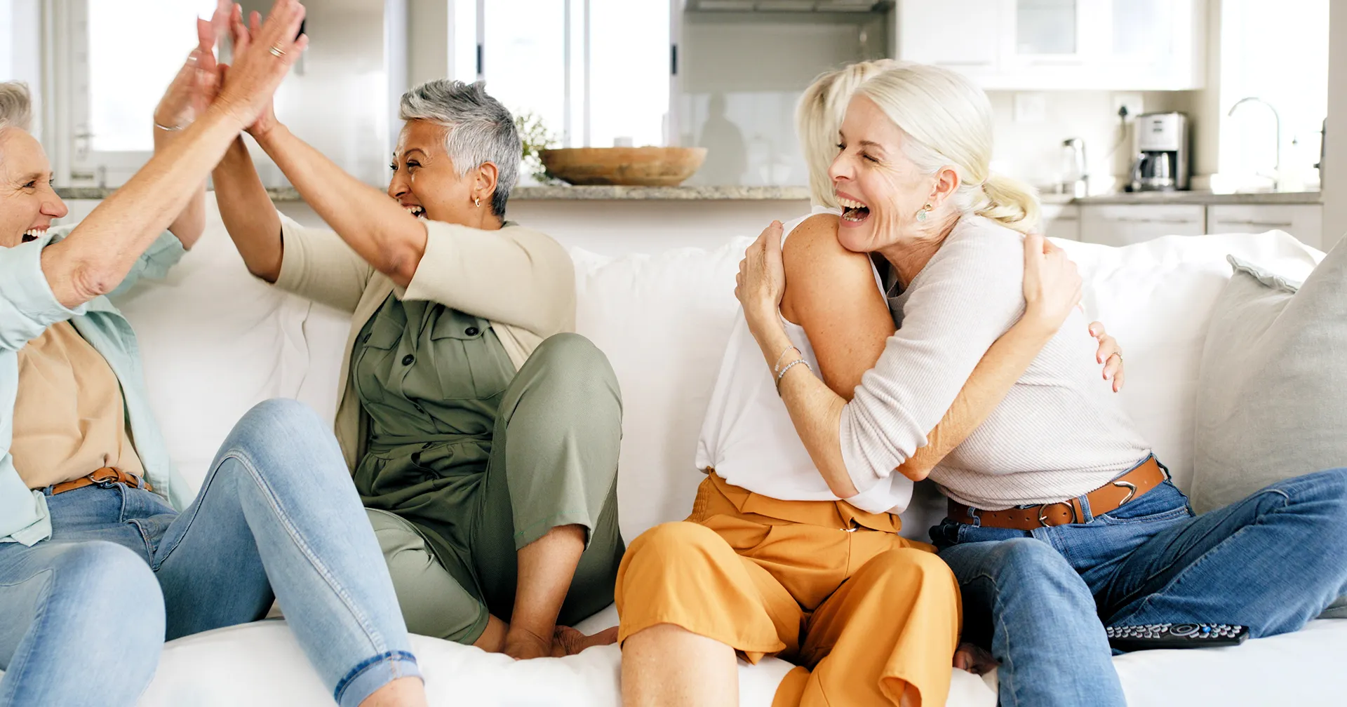 Blije vrouwen op een bank die elkaar omhelzen en een high five geven